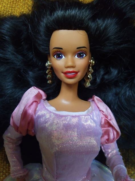 A Barbie Doll Wearing A Pink Dress And Gold Earrings On Top Of A Black