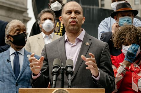 A Man Wearing A Face Mask Speaking At A Podium With Other People In The