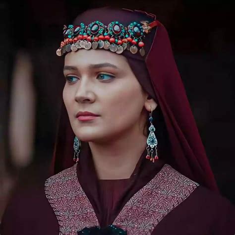A Woman Wearing An Elaborate Head Piece And Jewelry Is Looking Off To The Side With Blue Eyes