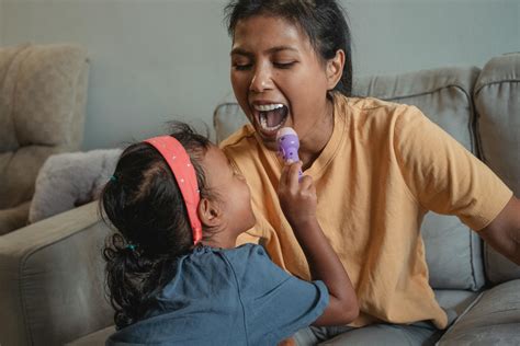 Feliz Madre étnica Con La Boca Abierta Jugando Al Doctor Con La Hija