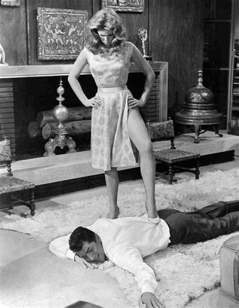A Woman Standing Next To A Man Laying On The Floor In Front Of A Fireplace