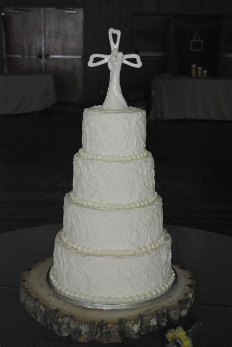 A White Wedding Cake With A Cross On Top