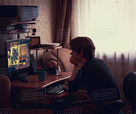 Caucasian man watching computer screen at desk - Stock Photo - Dissolve