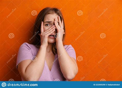 Young Ginger Scared Woman Looking At Camera While Covering Her Face