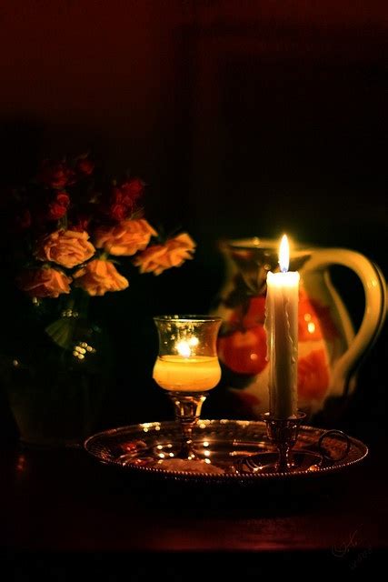 A Lit Candle Sitting On Top Of A Table Next To A Vase Filled With Flowers