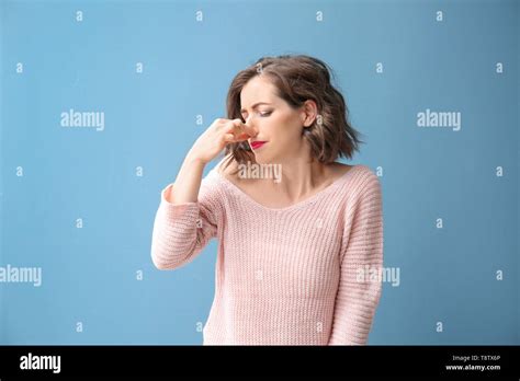 Portrait Of Beautiful Woman Pinching Nose On Color Background Stock