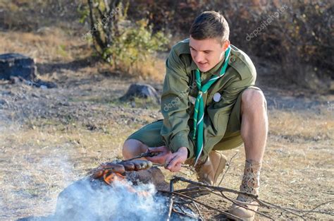 Boy Scout Cooking Sausages On Sticks Over Campfire Stock Photo By