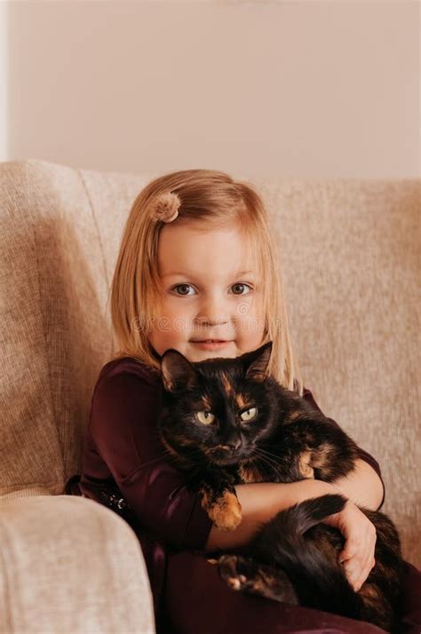 Little Cute Girl Holds A Black Cat In Her Arms Girl At Home With Her