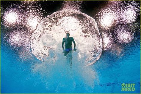 A Man In A Wet Suit Swimming Under The Surface Of A Pool With Bubbles On It