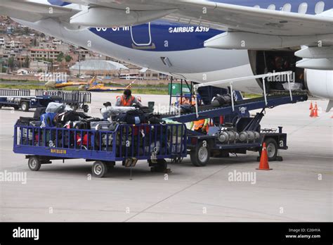Baggage Handlers At Airport Loading The Luggage Into The Aircraft Belly