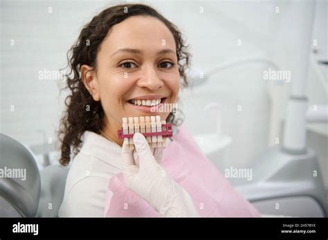 Close Up Of Dentist Hand Holding A Teeth Color Chart Near The Face Of A