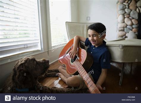 Dog Watching Smiling Boy Play Guitar Stock Photo Alamy