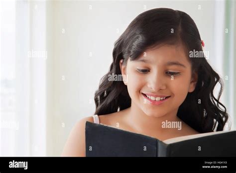 Portrait Of Smiling Cute Girl Reading Book Stock Photo Alamy