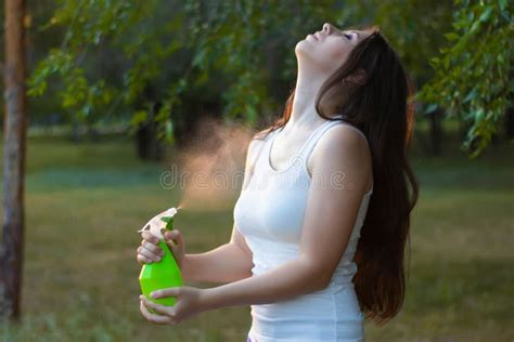 Young Woman Spraying Water On Herself From A Spray Bottle In A Summer