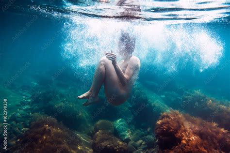 Naked woman with bubbles is underwater swimming in ocean ภาพถายสตอก