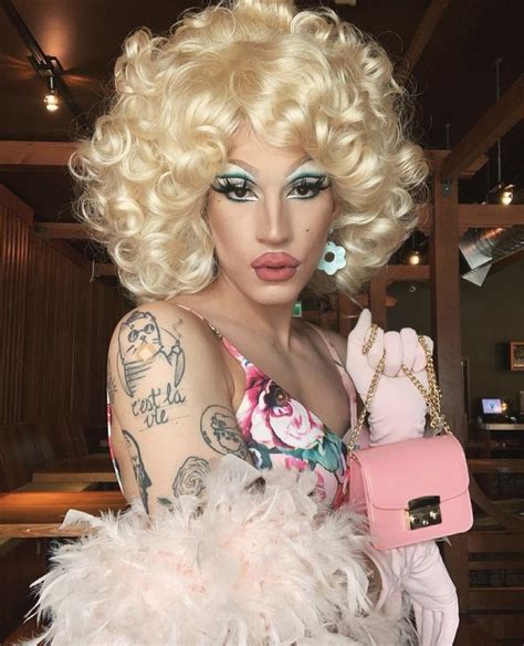 A Woman Dressed As A Drag Queen Holding A Pink Purse