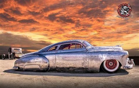 An Old Car Sitting In The Middle Of A Desert Under A Colorful Sky With