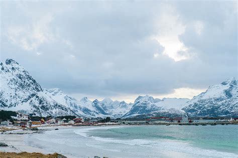 Distant View Of Waterfront Village And Snow Capped Mountains Reine