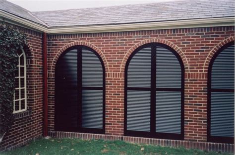 Arched Louvered Exterior Shutters Used To Enclose A Brick Breezeway