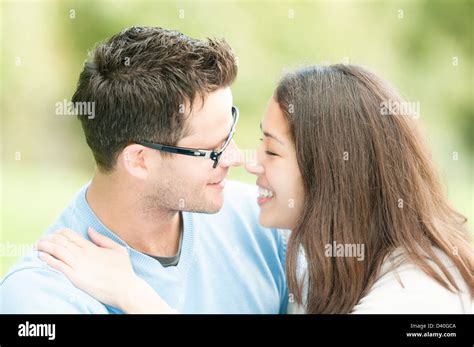 handsome man in glasses and pretty woman kissing outdoors husband and wife giving kiss to each