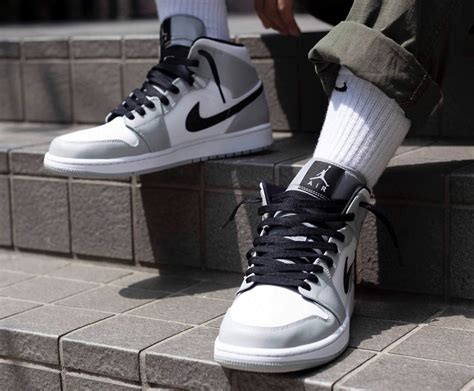 Built with leather, the upper sports a white base overlaid by light smoke grey, with black on the swoosh, laces and 'wings' branding. Nike Air Jordan 1 Mid Smoke Grey Low