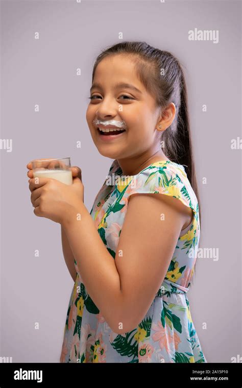 Portrait Of A Smiling Girl With Milk Moustache Drinking Milk In A Glass