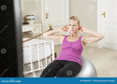 Woman Exercising Whilst Watching Fitness Dvd On Television Stock Photo