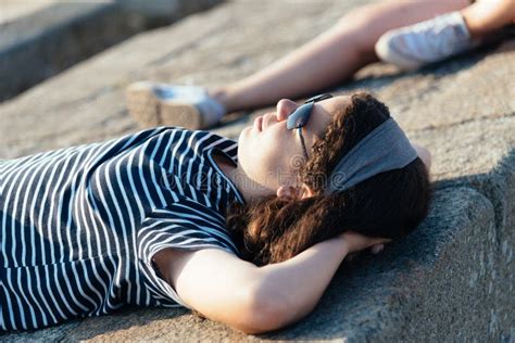 Portrait Of Beautiful Girl Relaxing Lying On The Walls Facing The Sun