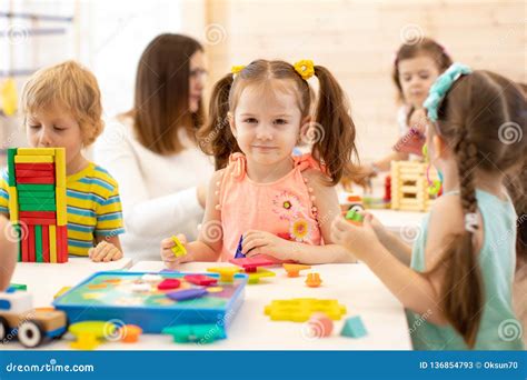 Preschool Children Play With Colorful Didactic Toys At Kindergarten