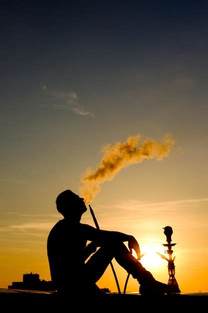 Silueta Del Hombre Fumando Narguile Sentado En El Techo Al Atardecer