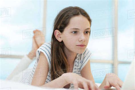 Preteen Girl Lying On Stomach Using Laptop Computer Stock Photo