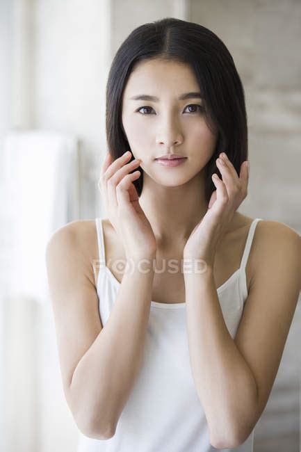 Portrait Of Beautiful Chinese Woman Touching Face Indoors Body Care Stock Photo