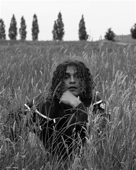a black and white photo of a woman sitting in tall grass