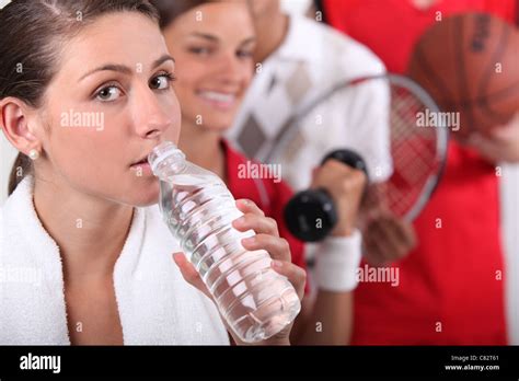 Sporty Young Girl Drinking Bottled Water With Other Young Sports People