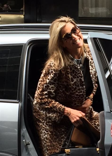 A Woman In A Leopard Print Coat Getting Out Of A Car With Her Handbag
