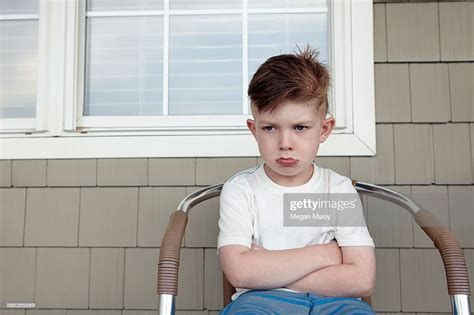 Portrait Of Boy Sitting Outside House Sulking High Res Stock Photo