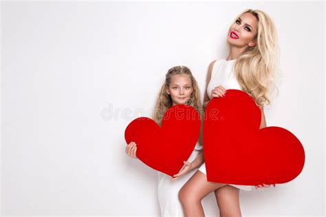 Beautiful Blonde Woman Mother And Daughter Standing On A White Background And Holding A Red