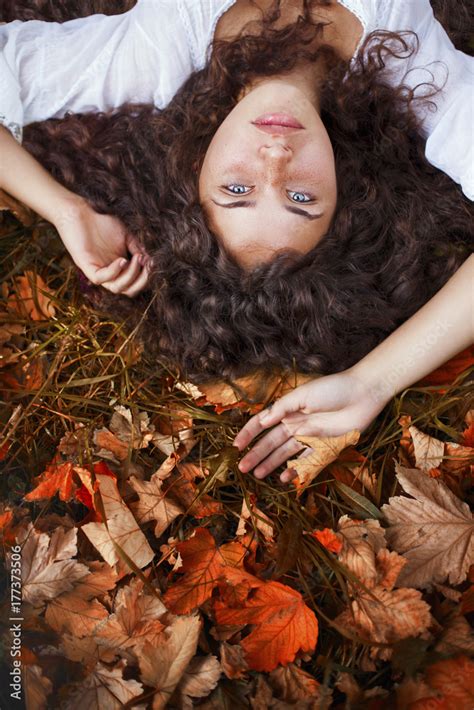 Beautiful Babe Woman With Curly Hair Blue Eyes And Freckles Lying On The Leaves Stock Photo