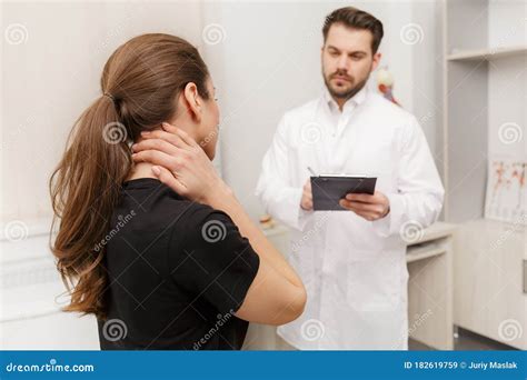 Male Doctor Examining Female Patient Suffering From Neck Pain Medical