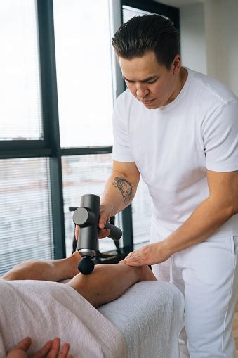Vertical Shot Of Professional Male Masseur Massaging Leg Calf Muscles