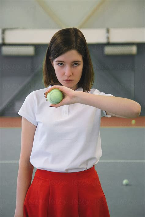 Girl Holding Tennis Ball In Front Of Her While Looking At Camera Del Colaborador De Stocksy