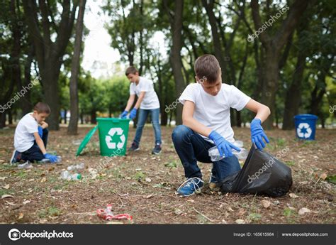 A Little Child Picking Up The Garbage And Putting It In A Black Garbage