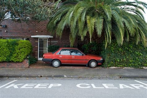 Image Of A Red Car Is Parked In Front Of An Apartment Block Next To A
