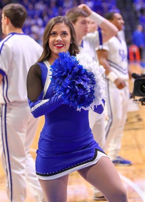 A Cheerleader Is Dancing On The Court With Her Pom Poms In Hand