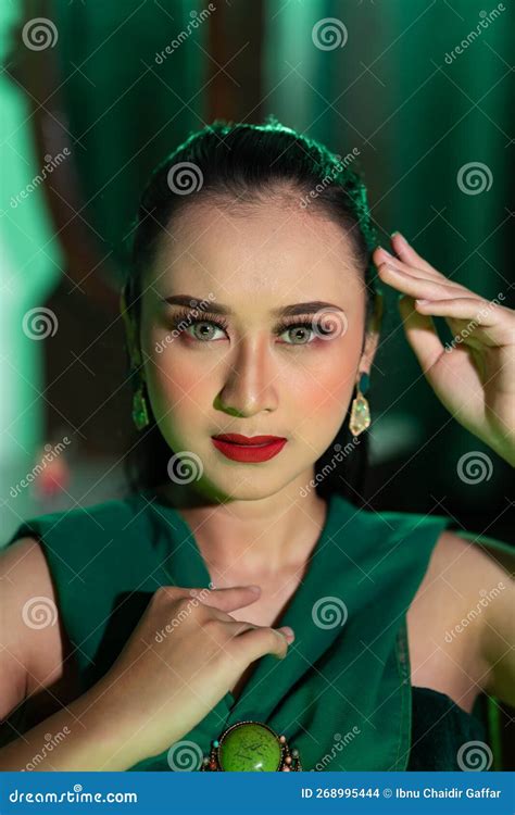 A Beautiful Asian Woman In A Green Dress Is Posing With Her Hands Very Gracefully And Has Green