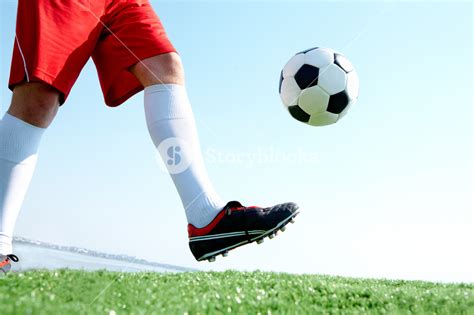 Horizontal Image Of Soccer Ball Being Kicked By Footballer Against Blue