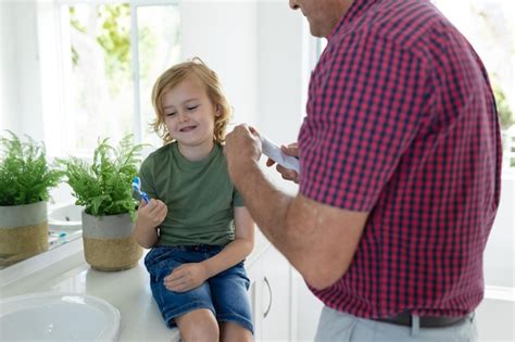 Premium Photo Caucasian Grandfather In Bathroom Brushing Teeth With Smiling Grandson Sitting