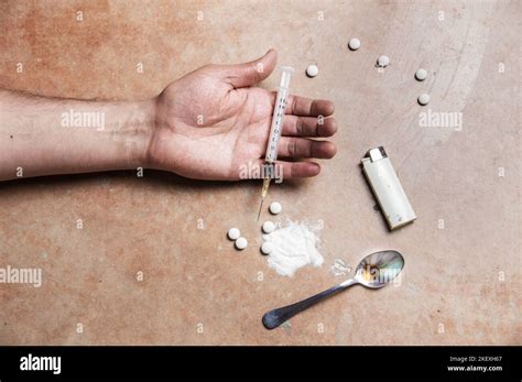 Close Up Shot Of A Drug Addicts Limp Arm With Drug Paraphernalia Lying