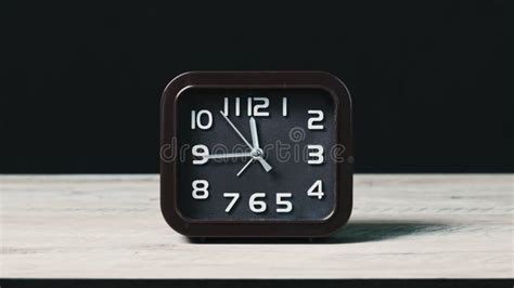 The Pointer Clock On A Wooden Table Shows The Time Stock Footage