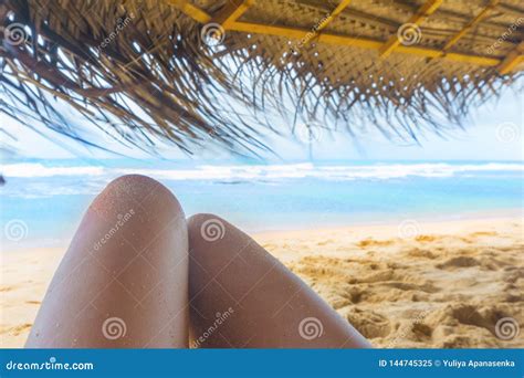 Womans Legs Under The Sunshade On The Sunny Tropical Beach Stock Image